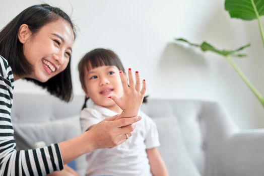 Mother and daughter having fun painting fingernails, family time concept