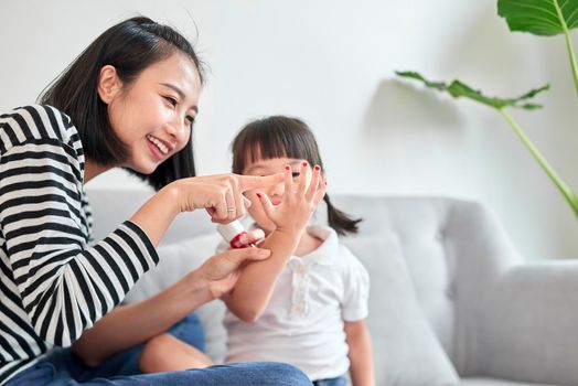 Mother and daughter having fun painting fingernails, family time concept