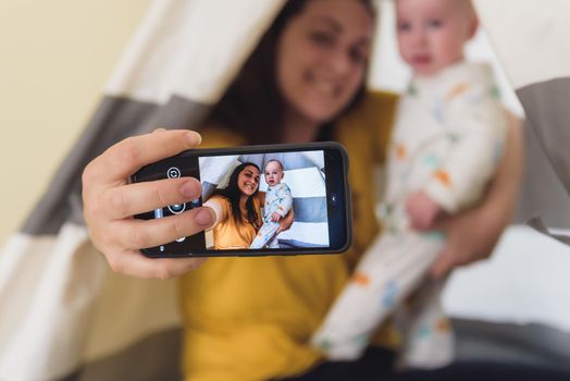 woman with her baby taking a picture while playing. family time.