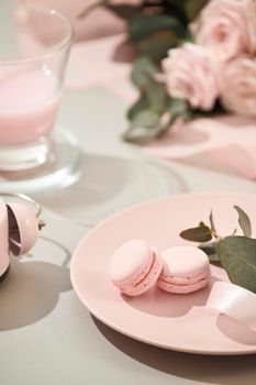 macaroons in pastel colors with bouquet of pink roses flowers on white background. Beautiful holiday background. copy space.