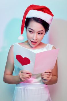 Image of happy beautiful female reading romantic postcard with big red heart,