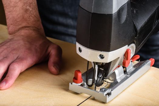 Man with electric jig saw cutting plywood