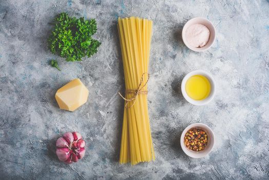 Raw ingredients for cooking linguine with olive oil, garlic and parsley. View from above