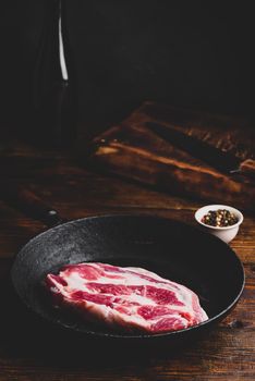 Raw pork neck steak in cast iron skillet