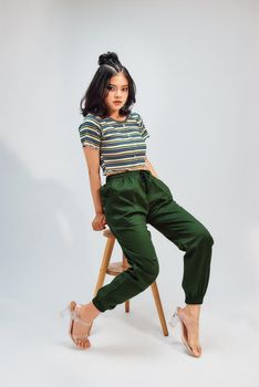 lifestyle, fashion and people concept: Full body portrait of fashion model sitting on wood chair in studio