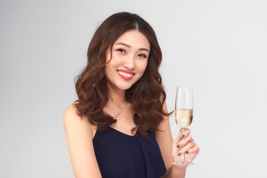 Young celebrating woman dark blue dress . Beautiful model portrait isolated over studio background hold wine glass.