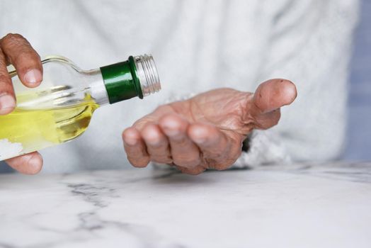 senior women pouring hair oil on hand.