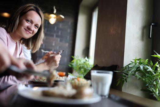 Young smiling woman is having lunch in cafe. Lunch break concept