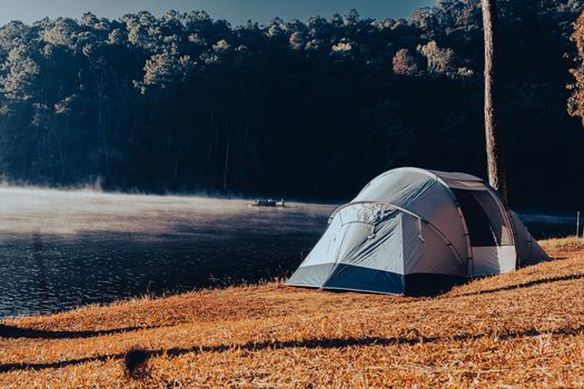 Camping tent by a beautiful lake over the misty river at sunrise. Concept of privacy tourism and freedom.