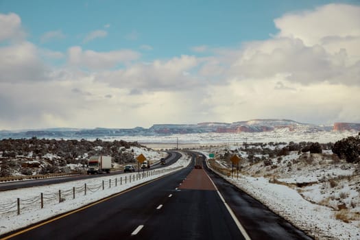 The snow-covered red rock mountain range behind desert landscape along I-40 highway in New Mexico USA