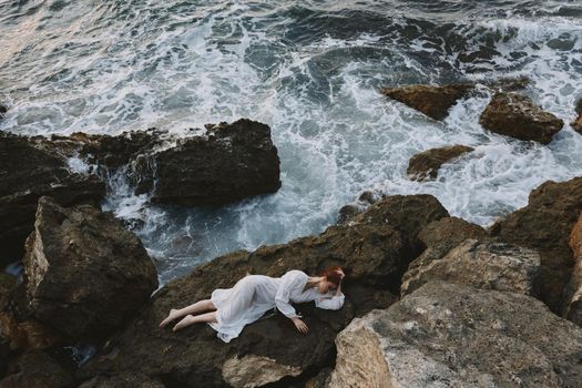 Barefoot woman in a white dress lying on a stone in a white dress vacation concept. High quality photo