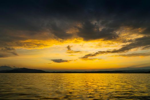 View of Lake Zugersee in the Swiss town of Zug at sunset with beautiful golden tones in the sky and reflected in the water and clouds.