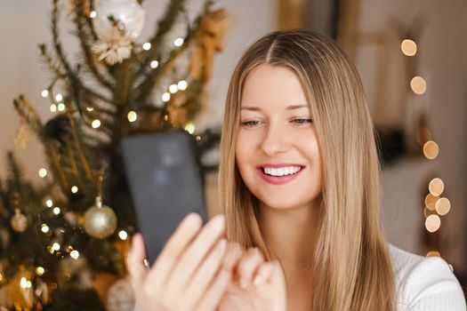 Christmas phone call and holiday greeting concept. Happy smiling woman using mobile smartphone on xmas day.