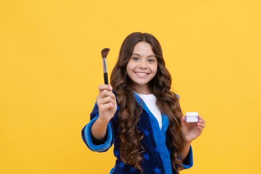 cheerful teen girl with curly hair in comfortable pajama use powder brush, cosmetology.