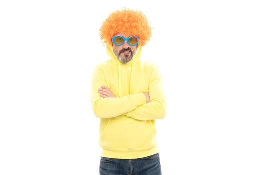 Funny man wear orange color wig with geeky look in party sunglasses keep arms crossed, extravagant.