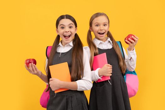 Happy kids in school uniforms hold books and apples for healthy eating school meal, snack.
