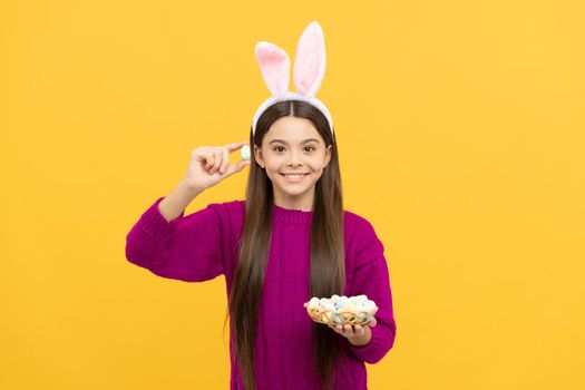 surprised teen kid in bunny ears with painted quail eggs for easter, easter hunt.