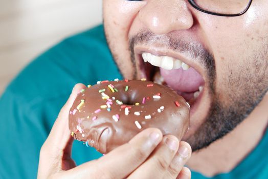 young man open his mouth eating donut , selective focus