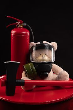 mascot of the fire brigade is a teddy bear in a gas mask with a fire extinguisher and a red axe in smoke on a dark background