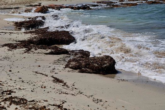 Waves against big rocks on the shore of the beach, turquoise water. Mediterranean Sea. Balearic Islands, sandy beach,