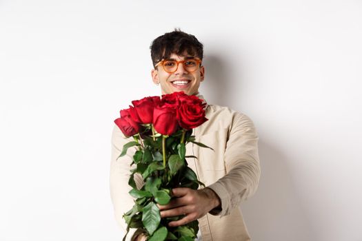 Handsome boyfriend giving you bouquet of roses, make surprise gift on romantic date at valentines day, standing with lover over white background.