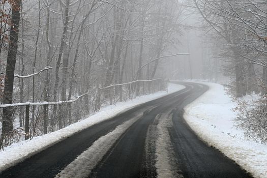 Bad weather driving - foggy hazy country road. Motorway - road traffic. Winter time and snow.