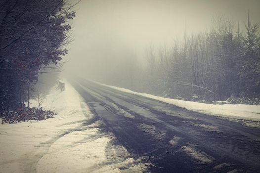 Snowy road with trees. Dangerous driving in the snow in winter. Concept for traffic and bad weather.