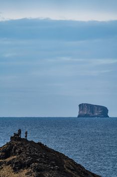 Tourists over the hill with huge islet in the background far in the ocean