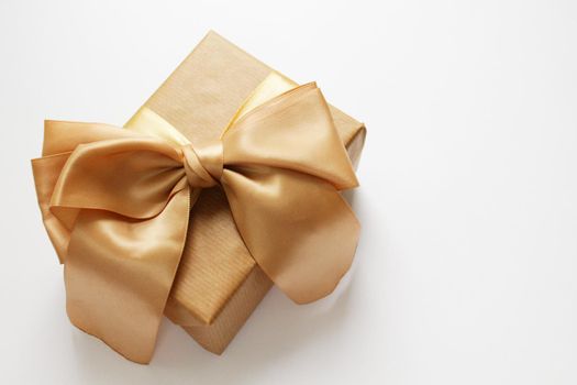 Gold gift box on a white background. Background, wrapping paper. White paper texture background. Gold ribbon.