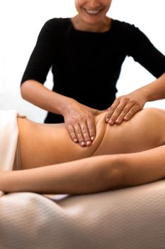 Happy masseuse working on female client mid back enjoying her job. Woman receiving massage relaxing in spa. Bodycare and luxury concepts.