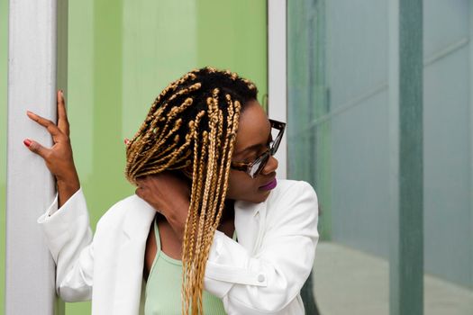 Young african american woman with long blond braids wearing sunglasses touching her hair. Lifestyle concept.