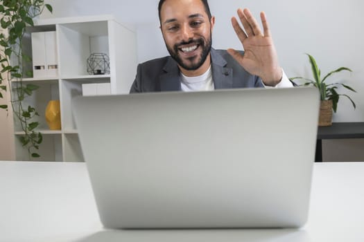 African american businessman on business video call waving his hand using his laptop. Entrepreneur greeting gesture to his colleagues from home office. Remote working concept. Technology concept.
