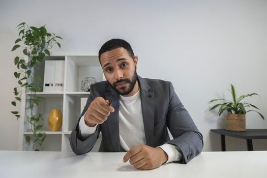 African american young businessman looking at camera talking to employee in video call. Pointing pen at camera in online business meeting. Business concept. Technology concept.