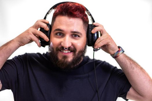Portrait of young man with red hair putting on headphones looking at camera. Entertainment concept.