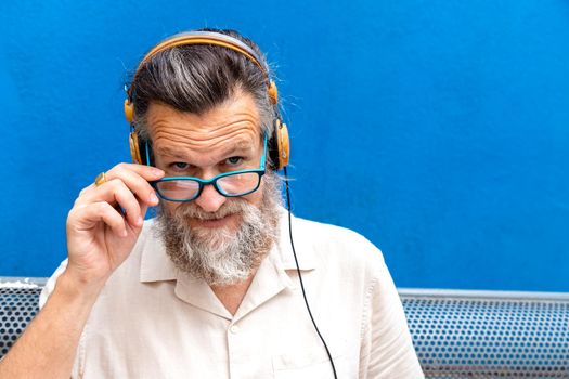 Portrait of mature caucasian man with headphones wearing eyeglasses looking at camera. Copy space. Headshot.