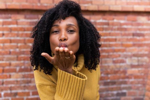 Young beautiful African American woman blowing kiss looking at camera. Copy space. Love and lifestyle concept.