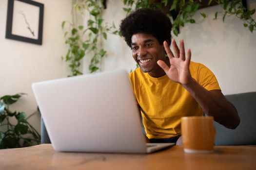 Smiling young African American man using laptop waving hello on a video call. Technology concept.