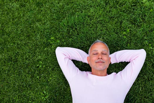 Adult caucasian man rest lying on grass with eyes closed. Copy space. Lifestyle and relaxation concept.