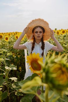 woman with pigtails in a straw hat in a white dress a field of sunflowers agriculture unaltered. High quality photo