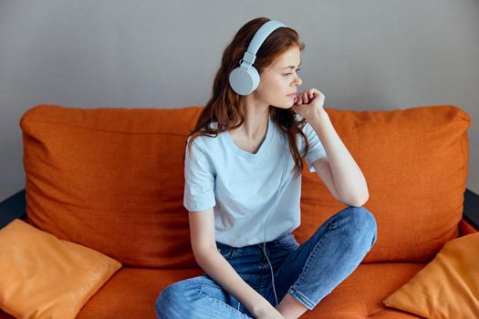 woman sitting on the couch at home listening to music on headphones apartments. High quality photo