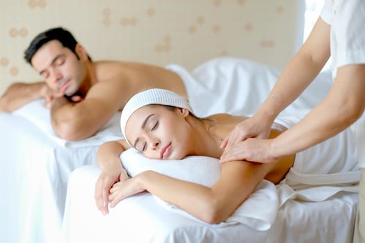 Young beautiful woman enjoy with massage in spa room with day light and the other man lie on bed beside her.