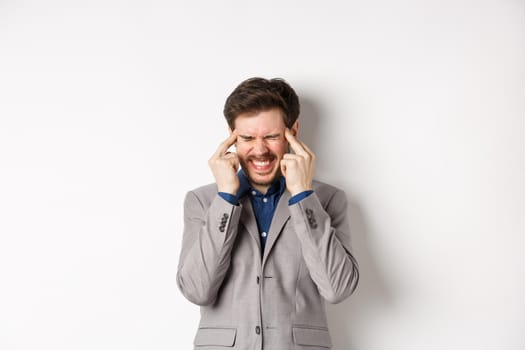 Image of frustrated man trying to think, cant remember something, touching head temples and squinting with tensed grimace, brainstorming, searching solution, white background.