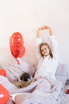 Happy valentines day. young woman lying on the bed and looking at red balloon