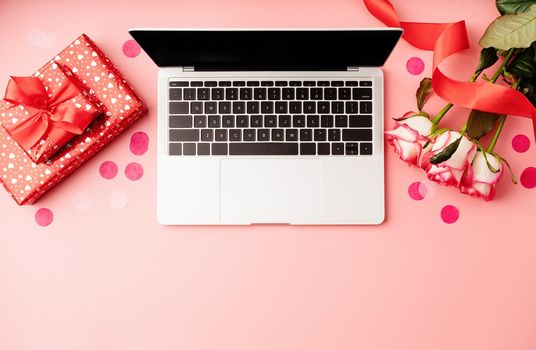 Valentines Day concept. Top view of valentines day workspace with laptop, flowers and gift boxes