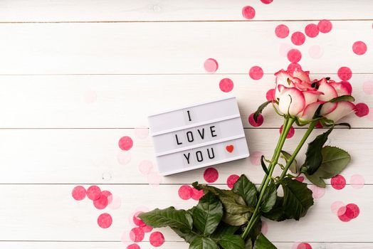 Valentines Day. i love you words on a lightbox with pink roses top view flat lay on white background