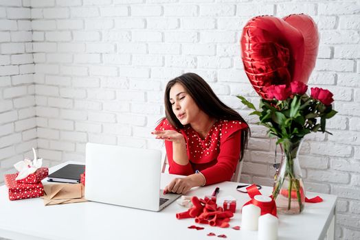 valentines day. Pretty young brunette woman dating online blowing a kiss over white brick wall background