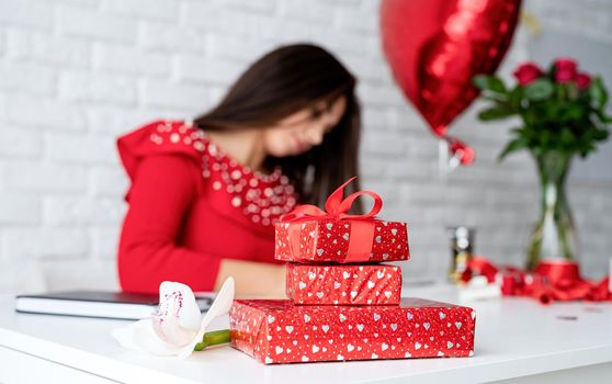 Happy birthday or valentines day. Pretty young brunette woman holding small gift box with ribbon over white brick wall background