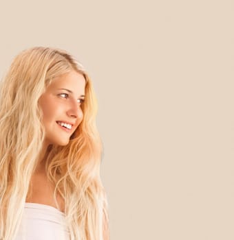 Beauty, hairstyle and wellness portrait. Happy smiling woman with long blonde hair on beige background, natural look.