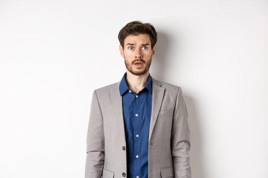 Confused bearded businessman in suit looking at upper right corner logo concerned, standing nervous on white background.