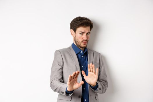 Stay away. Reluctant businessman step back with concerned disgusted face, raising hands to block bad offer, rejecting something awful, telling no and decline proposal, white background.